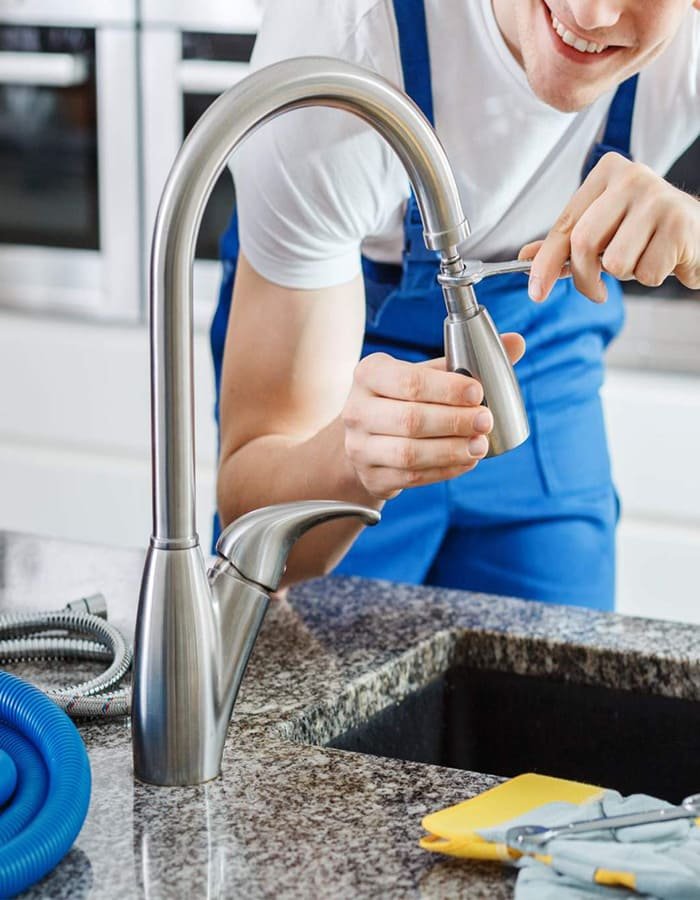 Plumber repairing pipes under sink